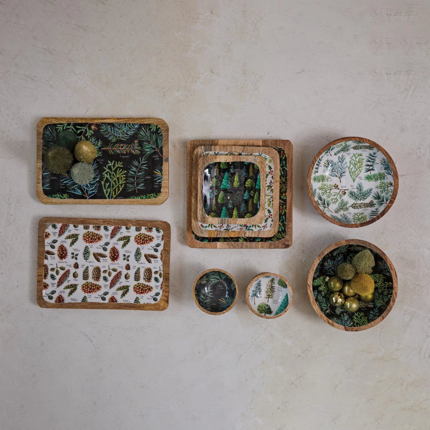 top view of the evergreen botanicals enameled mango wood tray displayed next to other evergreen botanicals pieces