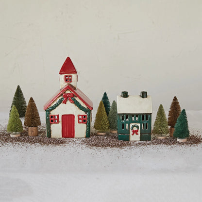 hand painted stoneware church displayed next to a stoneware house and bottle brush trees on a white surface