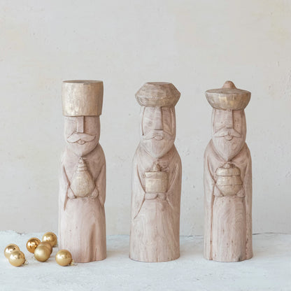 3 assorted wisemen carved from mango wood arranged on a table with a few gold ball ornaments.