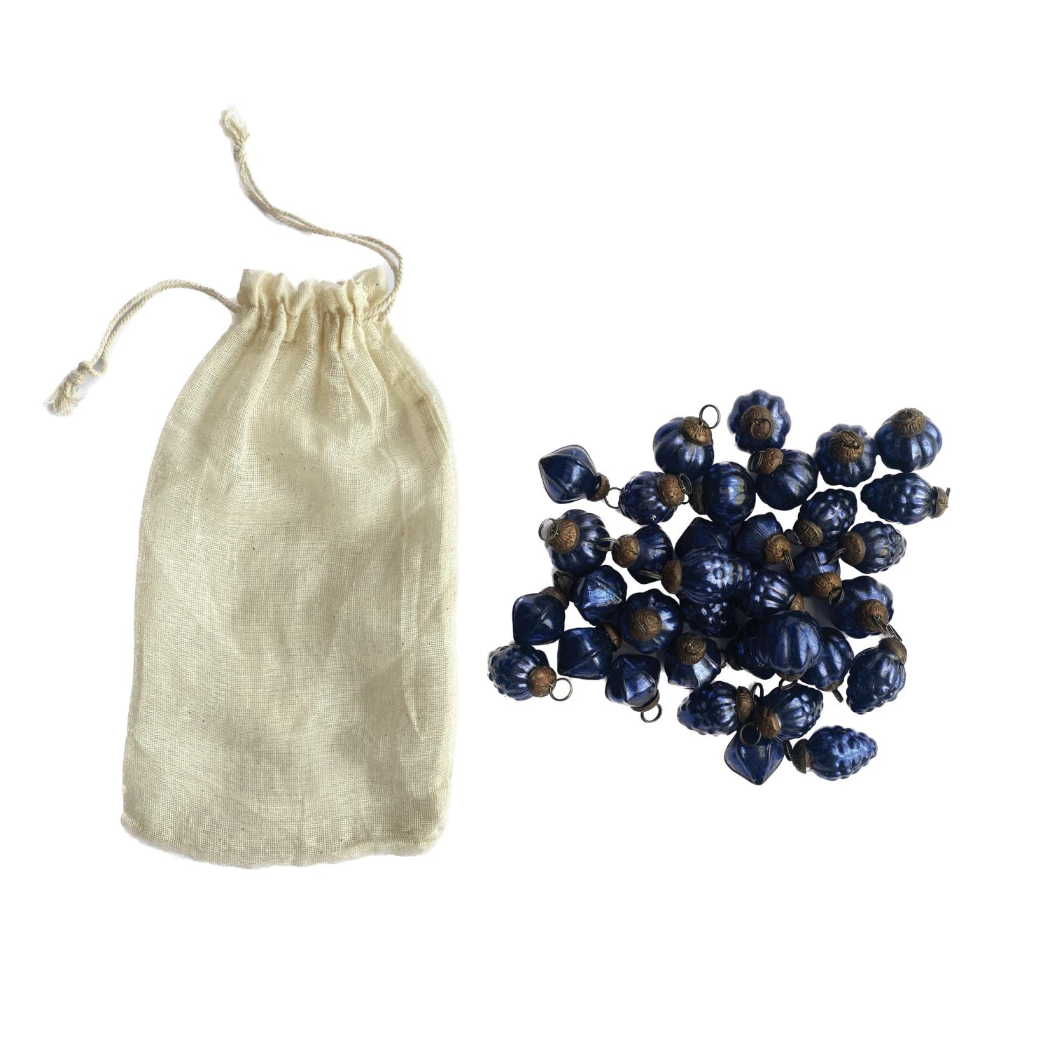 muslin bag with a pile of blue mercury glass ornaments next to it on a white background.