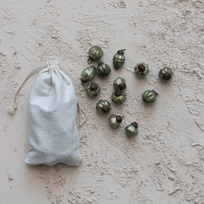 muslin bag filled with ornaments with several ornament scattered around it on a plaster surface.