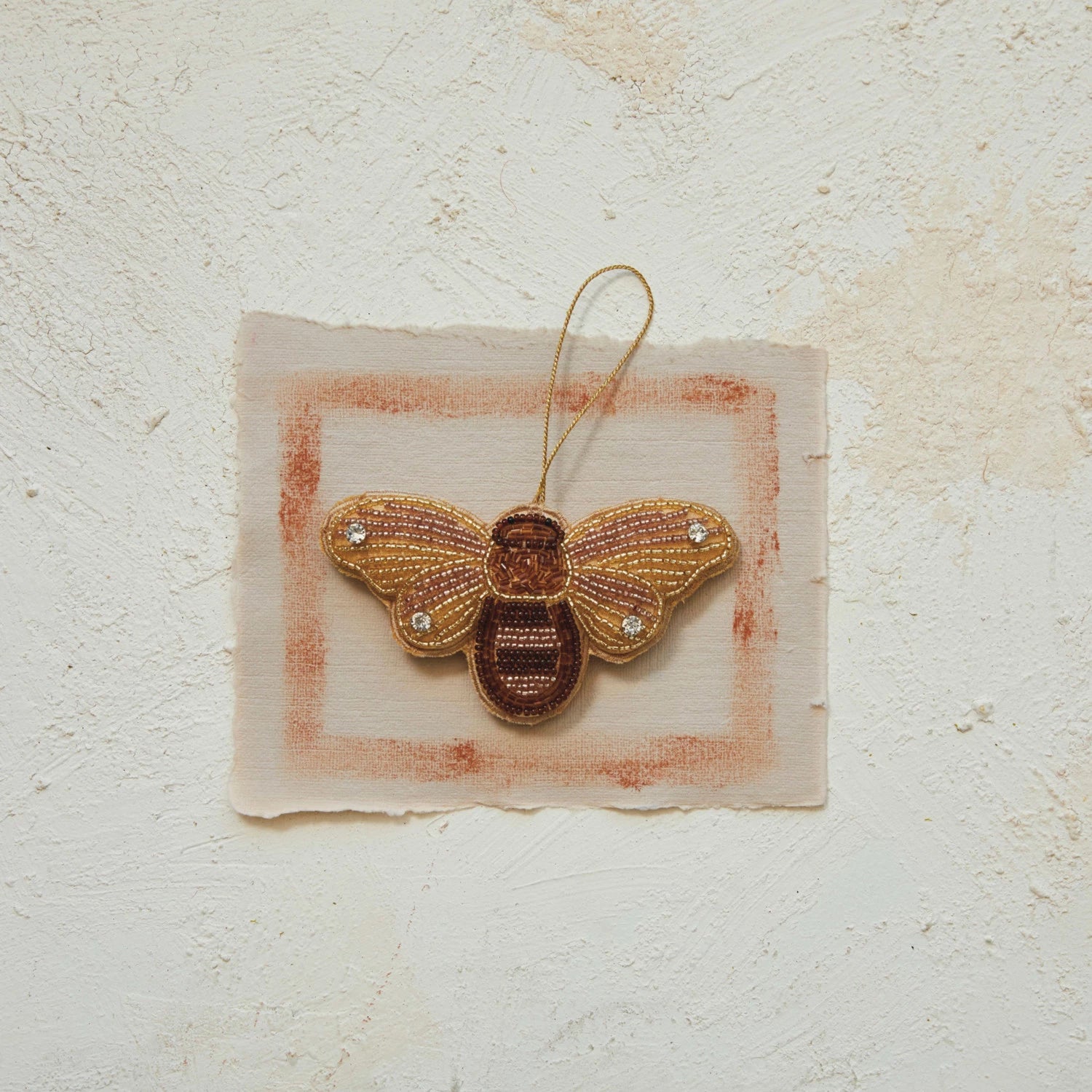 beaded bee ornament set on a bit of paper.