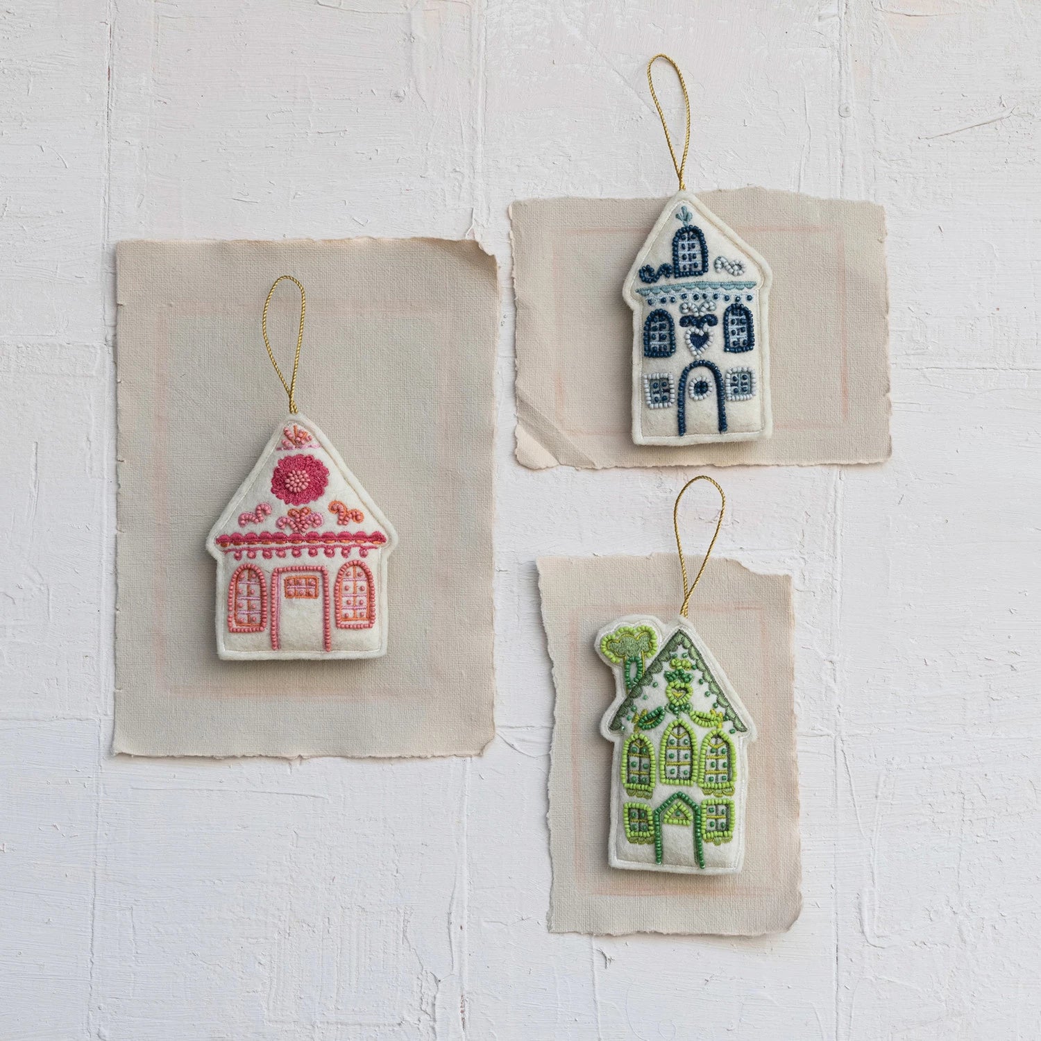 3 colors of felt houses arranged on bits of paper.