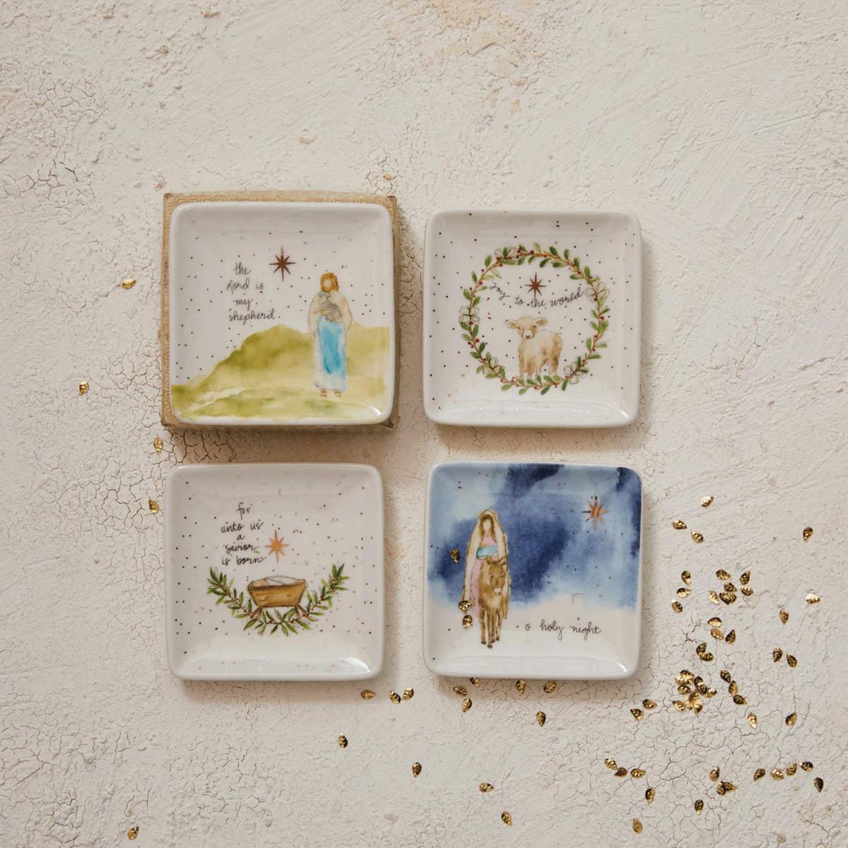 assorted Petite Square Christmas Dishes arranged on a plaster surface with gold confetti