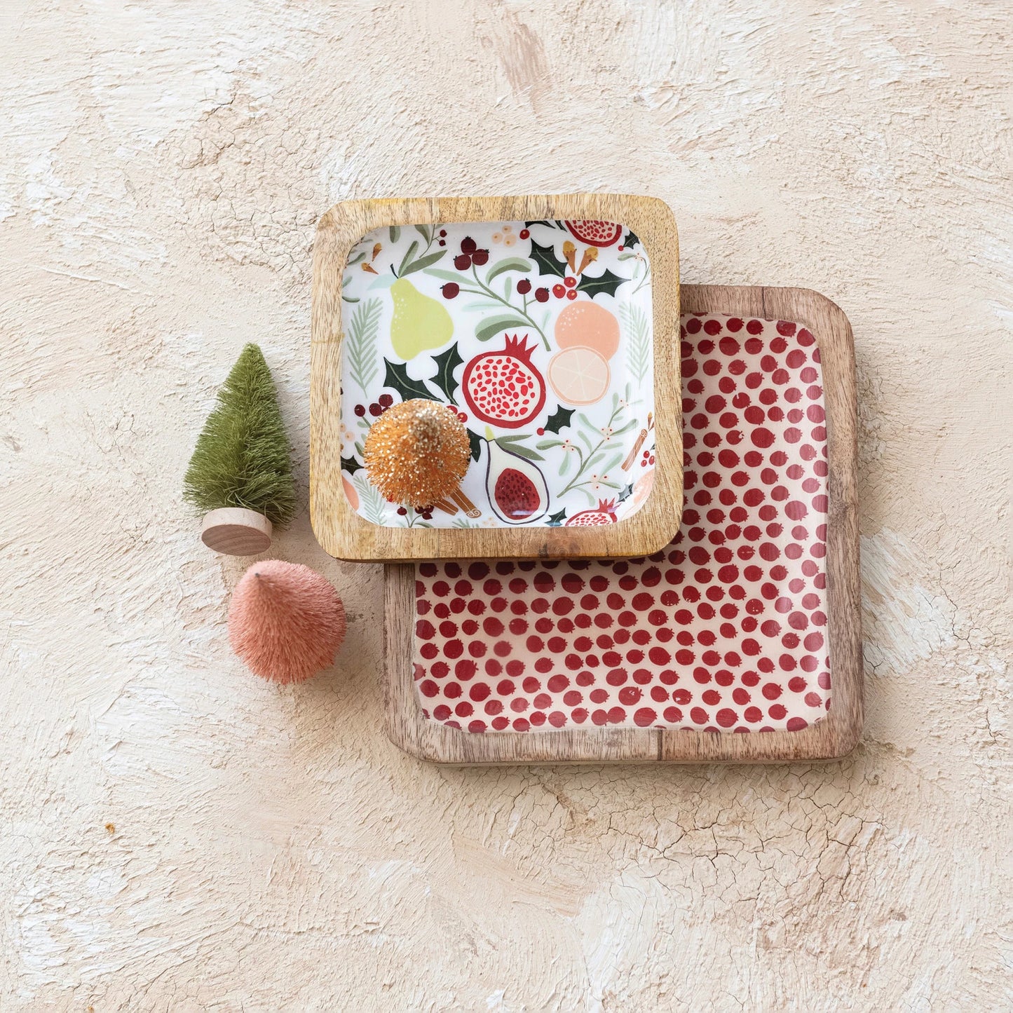 both styles of wood tray arranged on a plaster surface with small bottle brush trees.