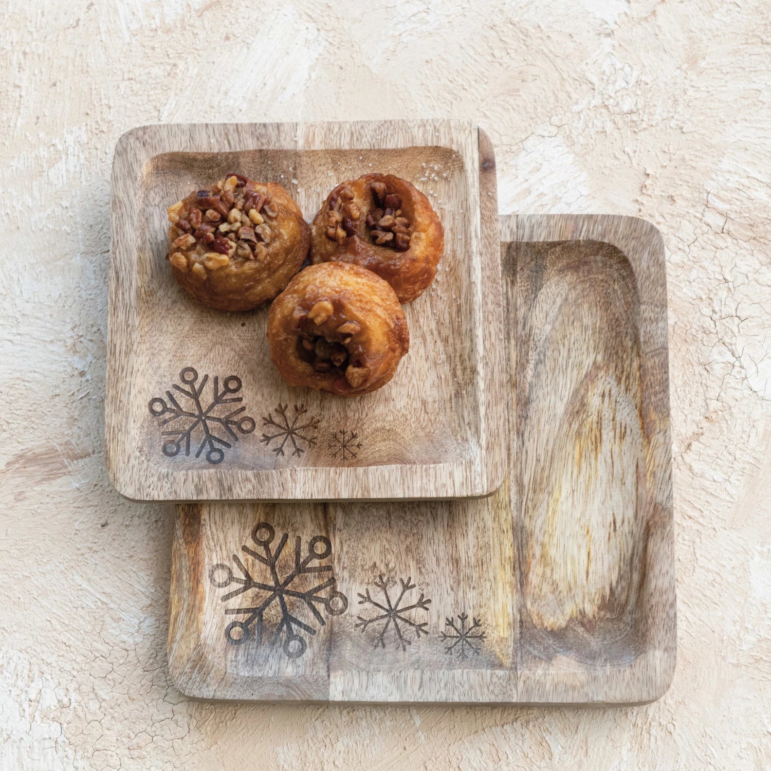 2 sizes of wooden trays with snowflake carved in the corner stacked with muffins on the smaller tray.