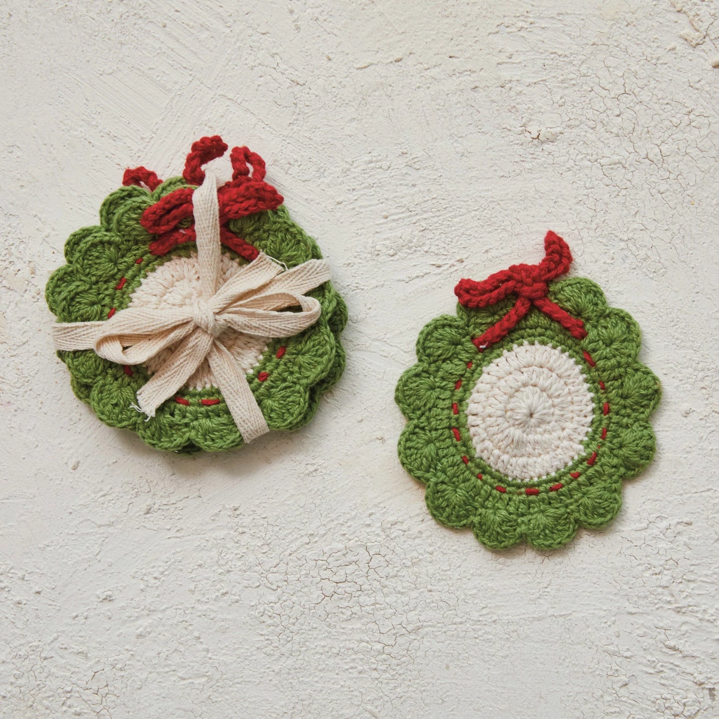 stack of  wreath costers tied together with a ribbon and another wreath coaster set next to it on a plaster background.