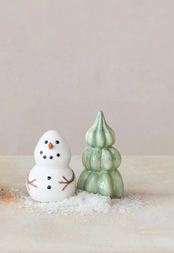 snowman and tree salt and pepper set on a table with salt and pepper scattered about.