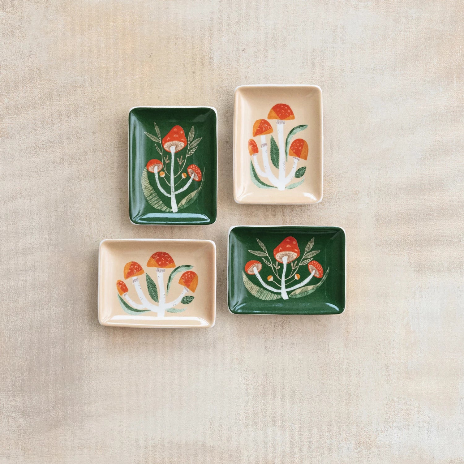 4 assorted stoneware mushroom dishes arranged on a plaster background.