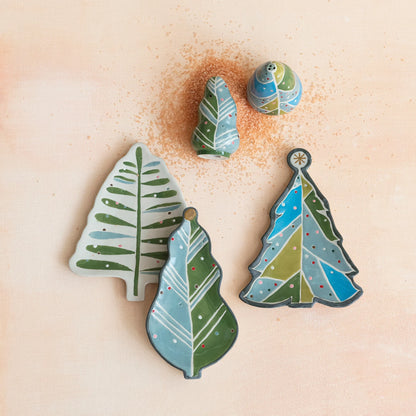 3 styles of tree shaped plates arranged on an off-white surface with salt and pepper shakers.