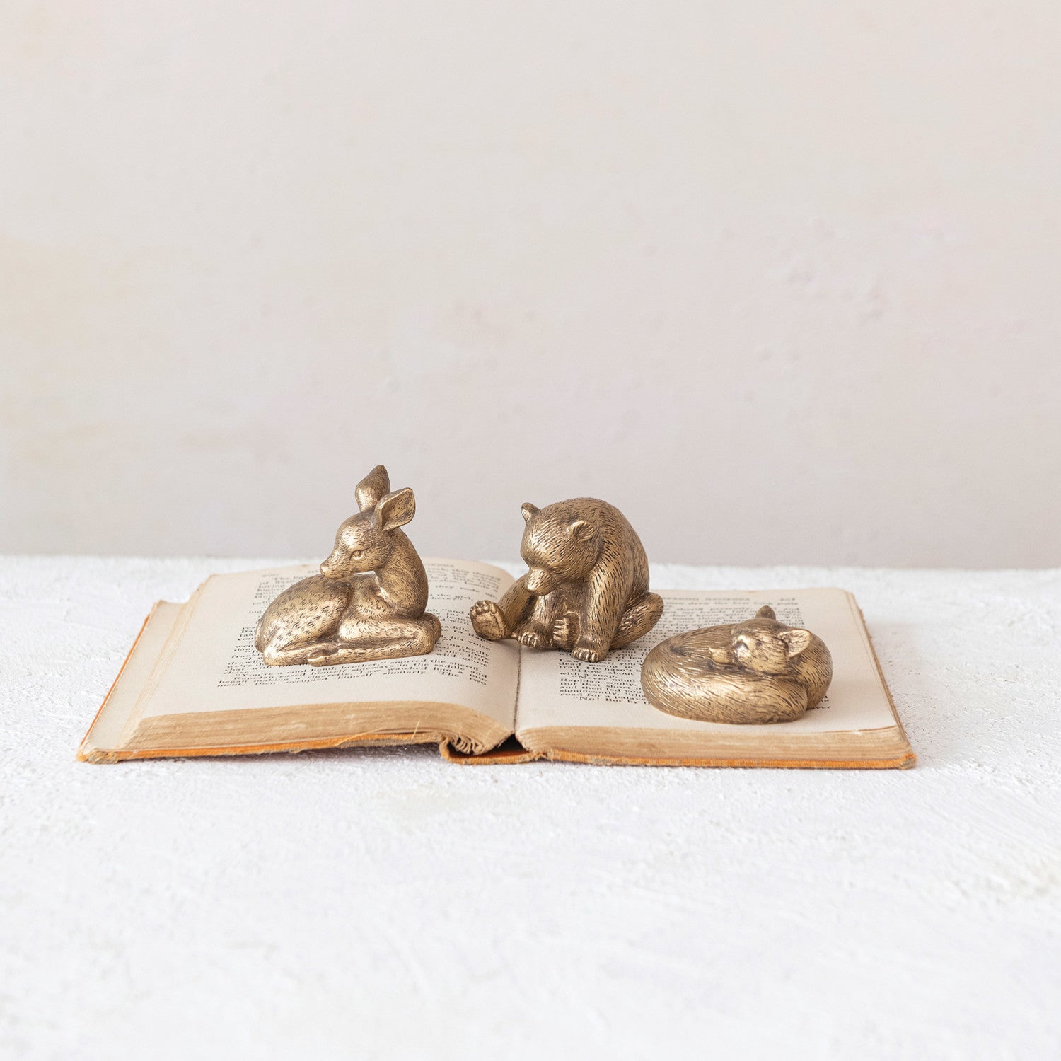 setting gold deer, bear, and fox laying on an old book