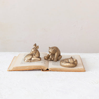 setting gold deer, bear, and fox laying on an old book