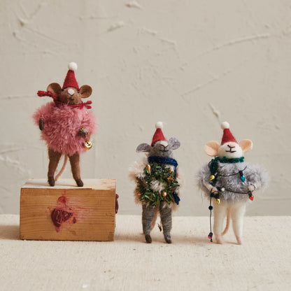 3 felt mice arranged on a table in front of a plaster background.