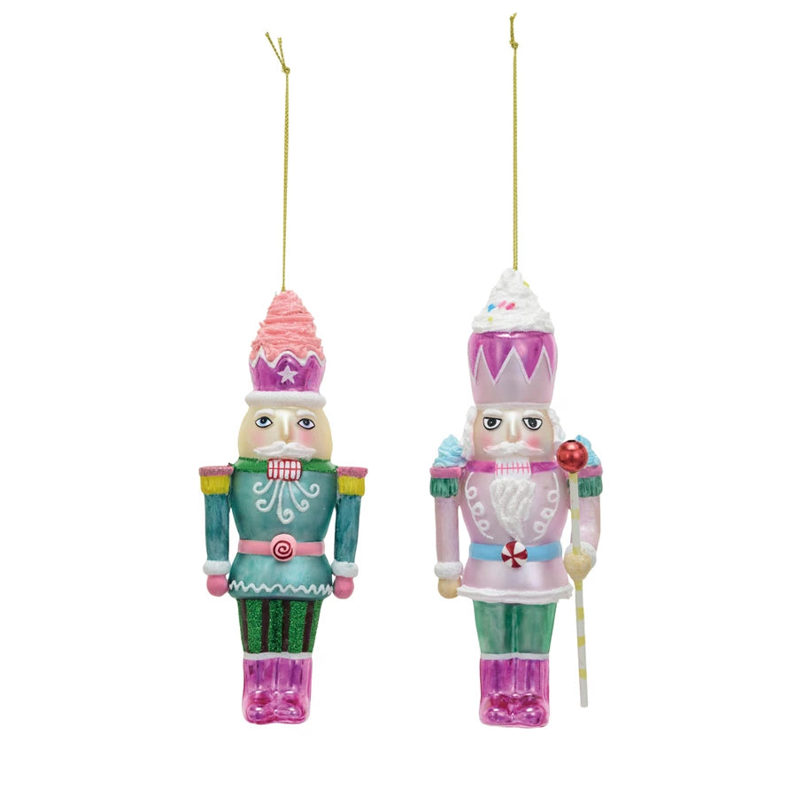 Pink and green glass nutcracker ornaments on a white background.