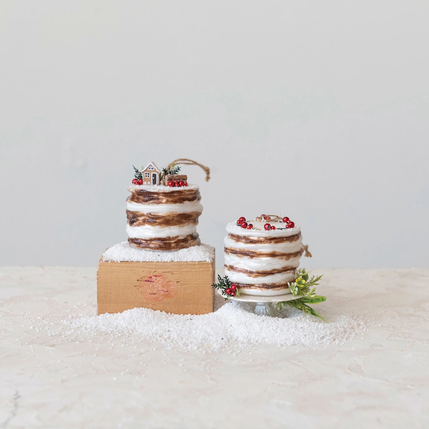 2 styles of glass cake ornaments surrounded by artificial snow.