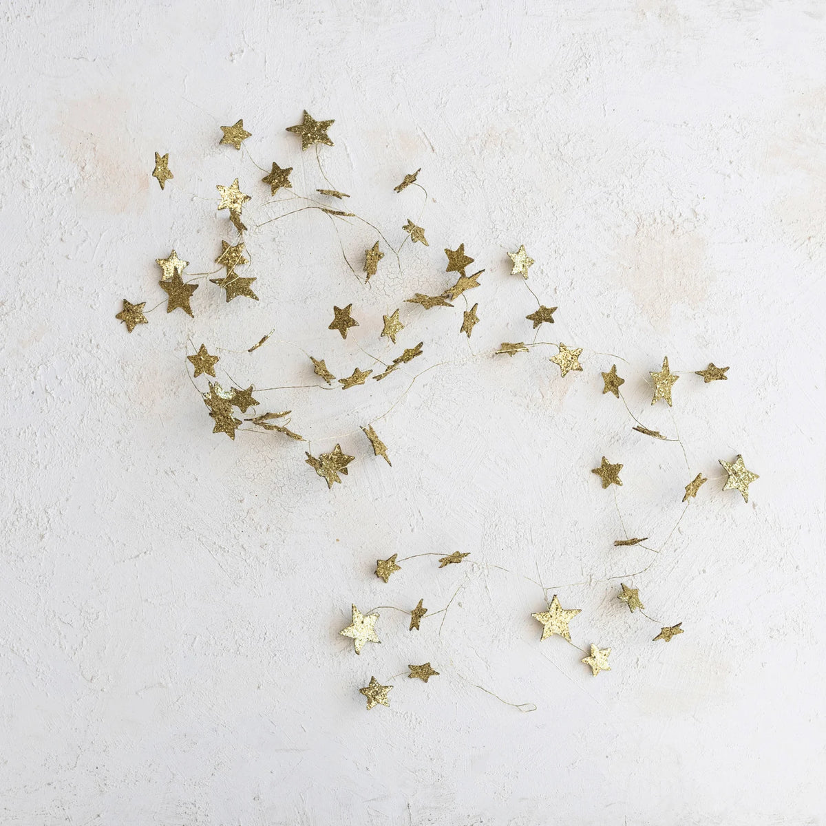 gold star glitter garland laying against a textured background