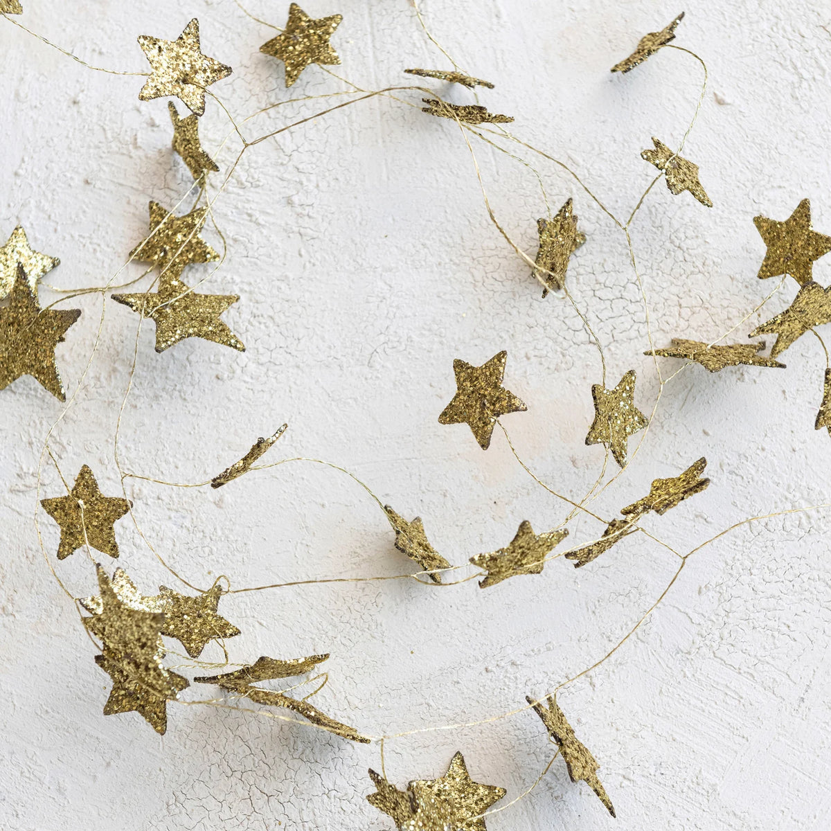 gold star glitter garland shown on a beige textured background