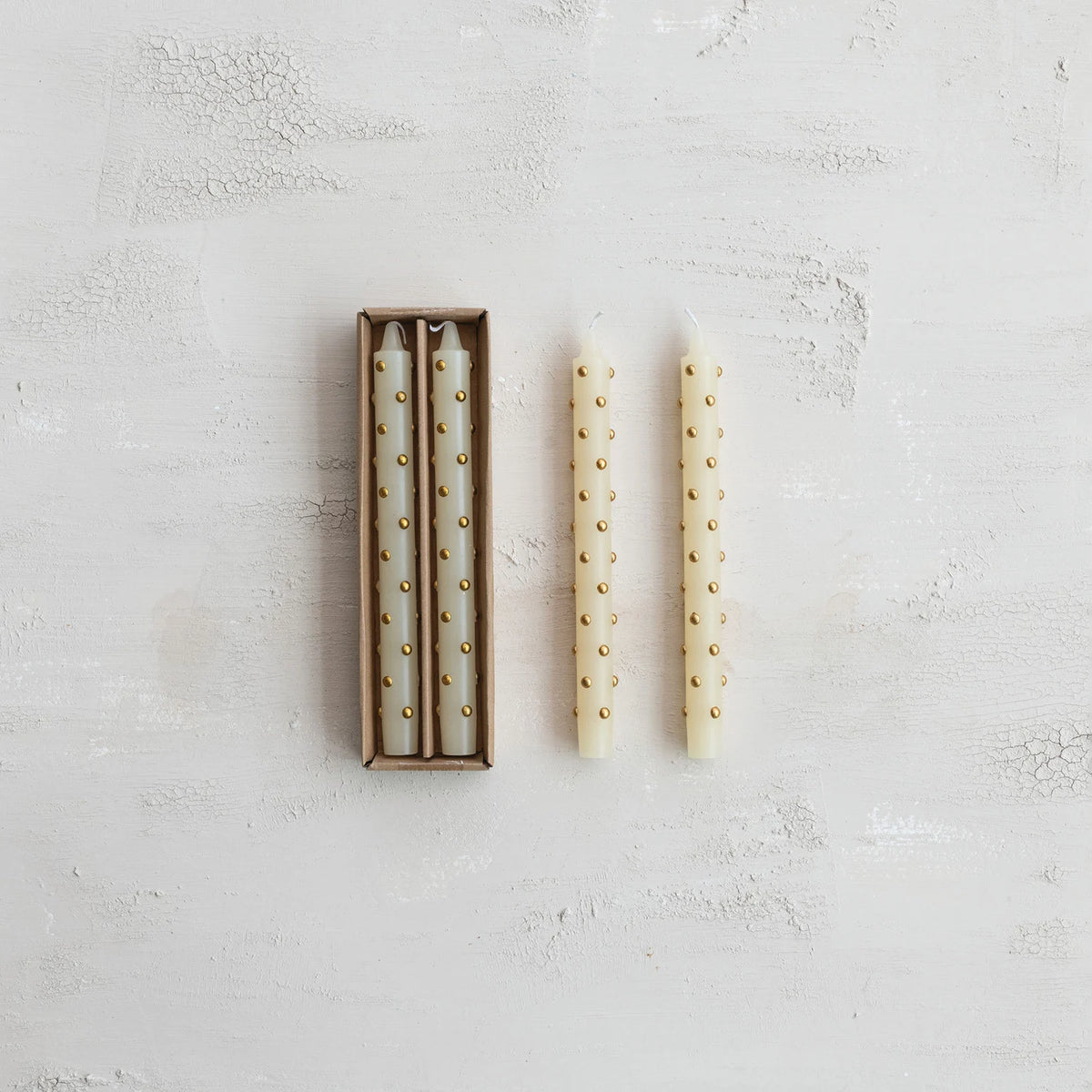 box set of ivory candles with 3d gold dots on them next to 2 candles out of their box