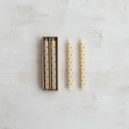 box set of ivory candles with 3d gold dots on them next to 2 candles out of their box
