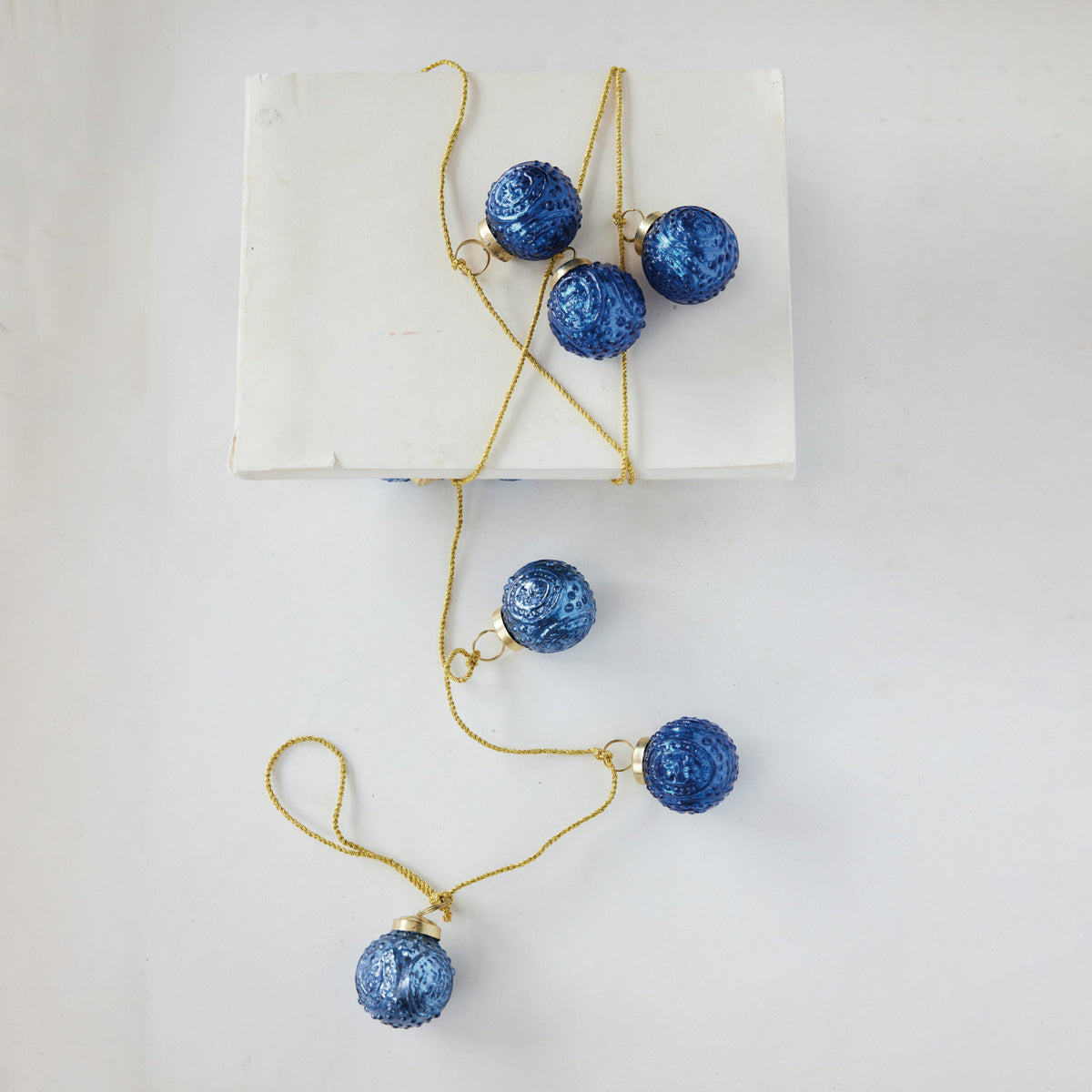 blue ornament garland wrapped around a stack of paper