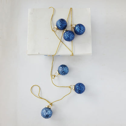 blue ornament garland wrapped around a stack of paper