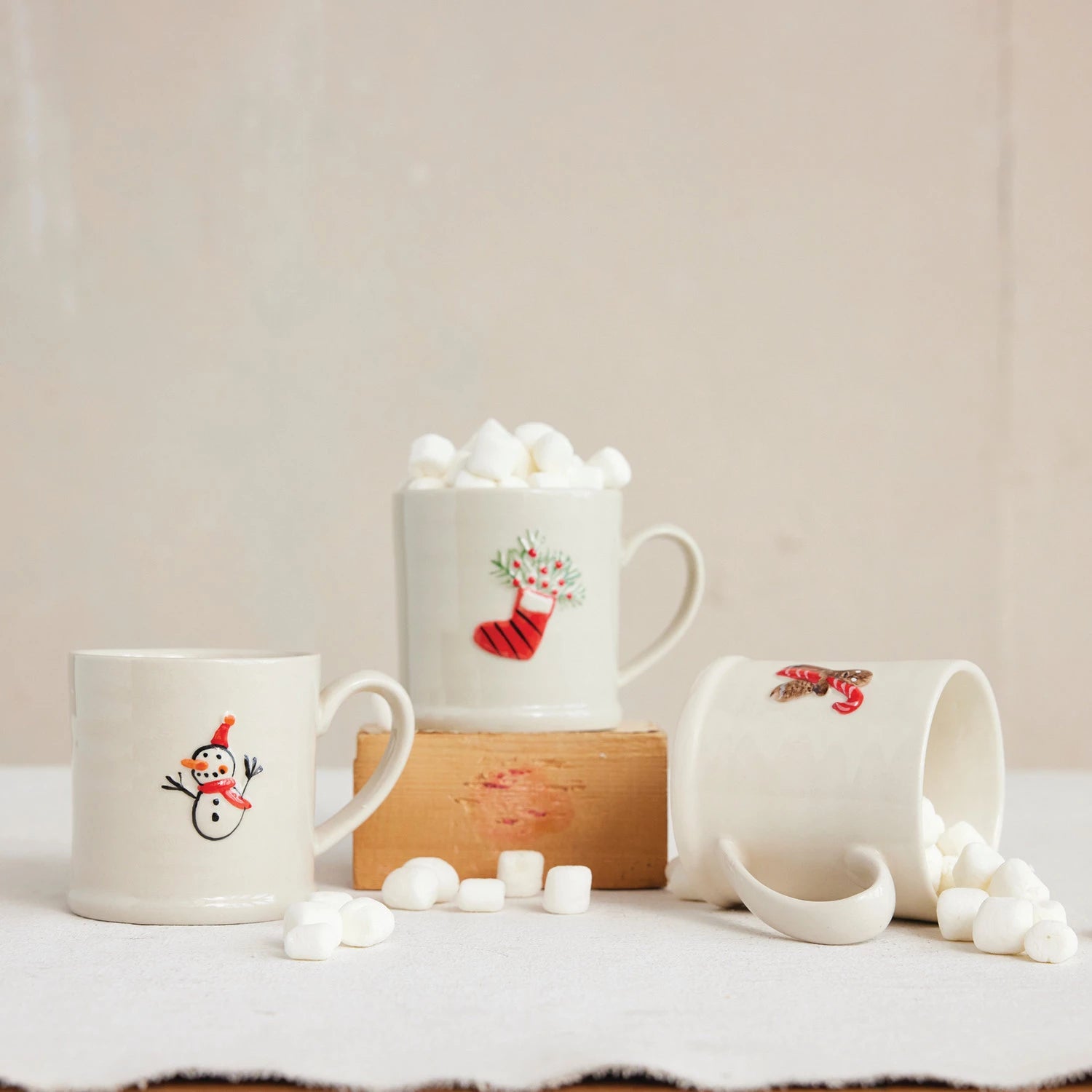 Embossed Stoneware Holiday Mugs arranged on a table with marshmallows