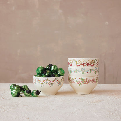 3 holiday bowls stacked up next to 1 bowl filled with overflowing green ornaments