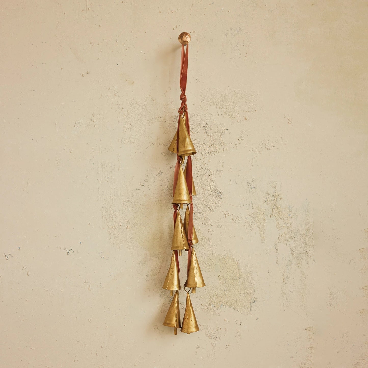 Metal Cone Bells on Velvet Ribbon hanging on a plaster wall