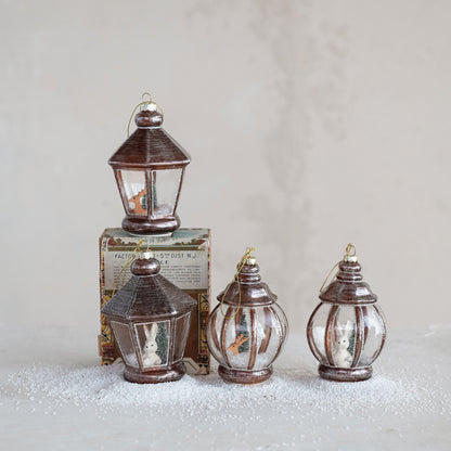 4 lantern ornaments arranged on a grey background with a sprinkling of artificial snow