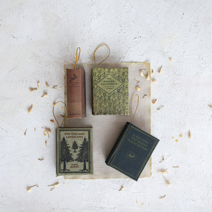 4 book ornaments on a decorated surface