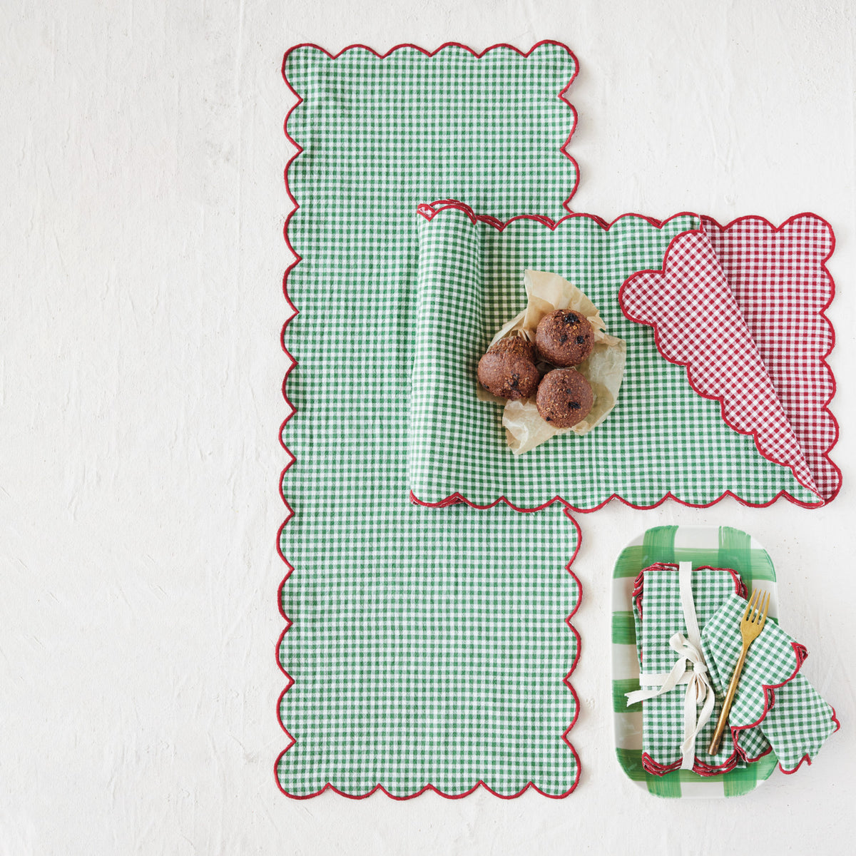 gingham table runners on an off-white surface, one is draped to show green on one side and red on the other