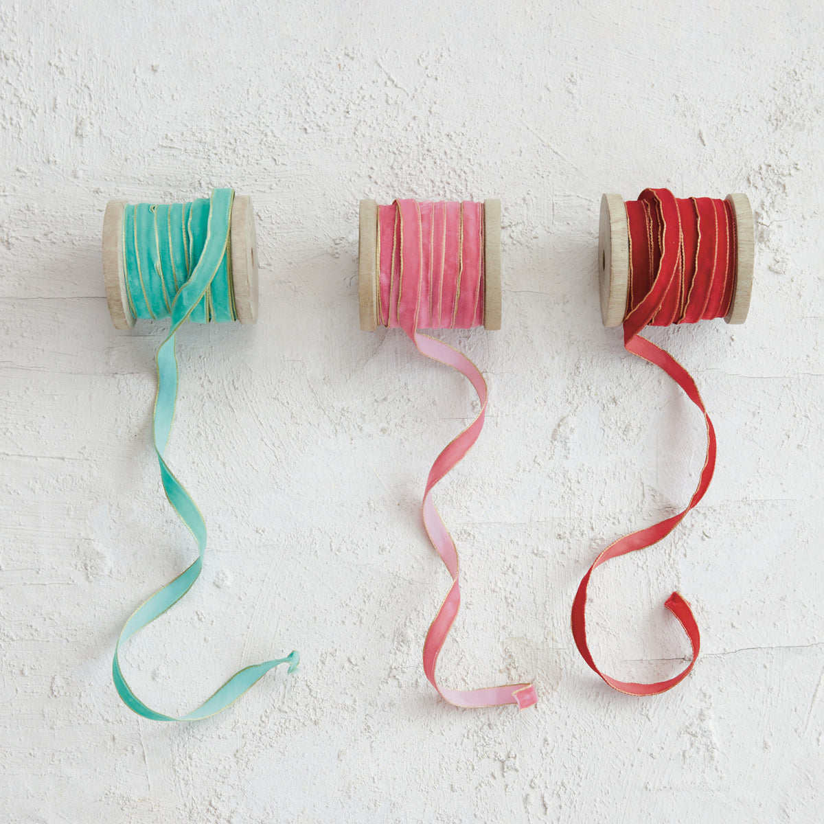 3 spools of ribbon on a white plaster background