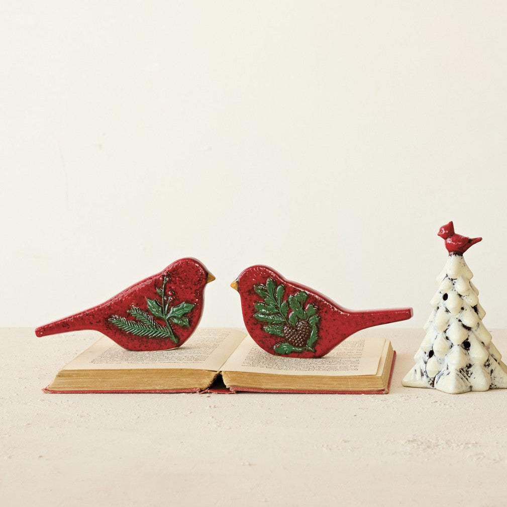 2 cardinal figurines set on an open book with a small white tree next to it