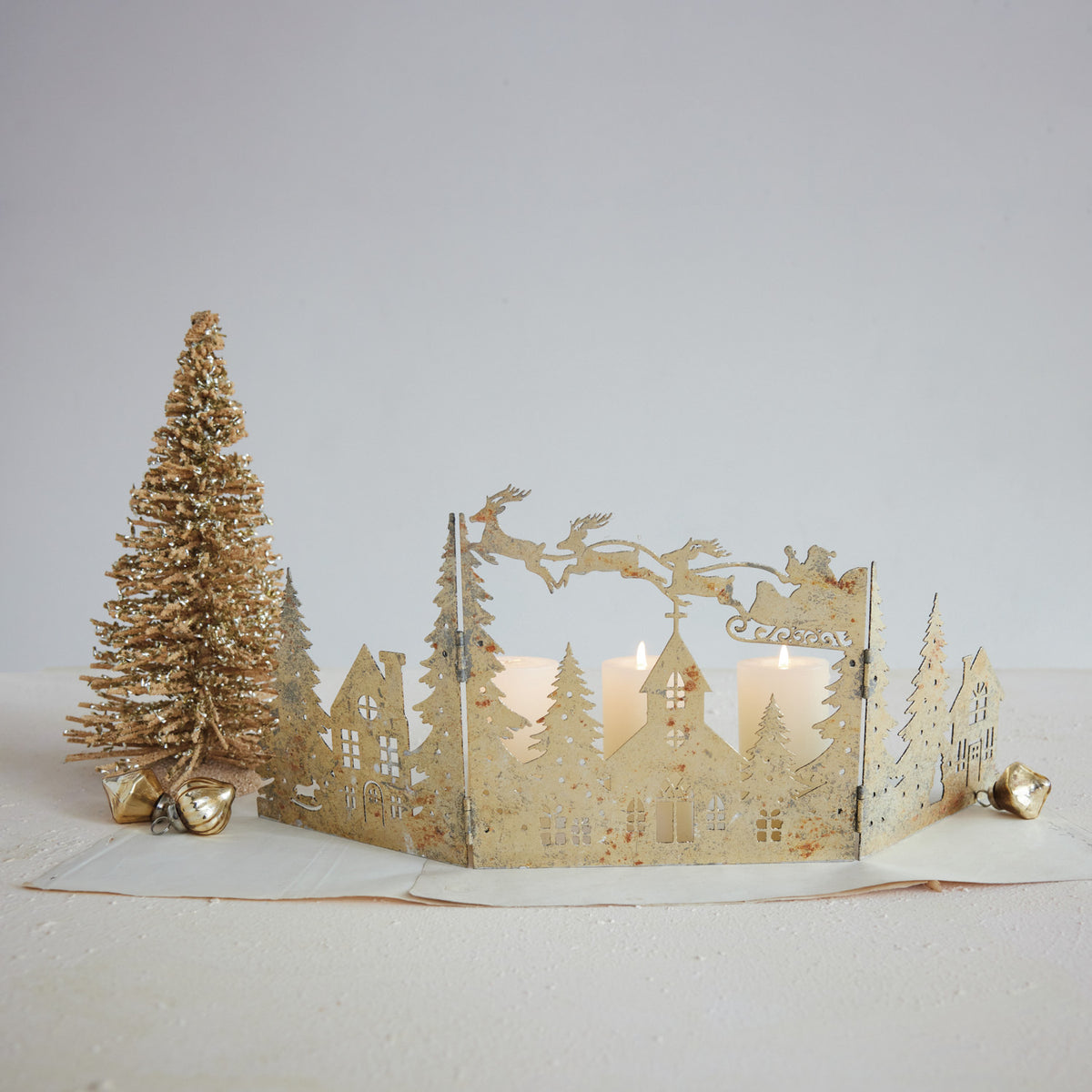 Distressed Gold Mantle Scene with Santa & Reindeer on a decorated setting with candles lit behind it