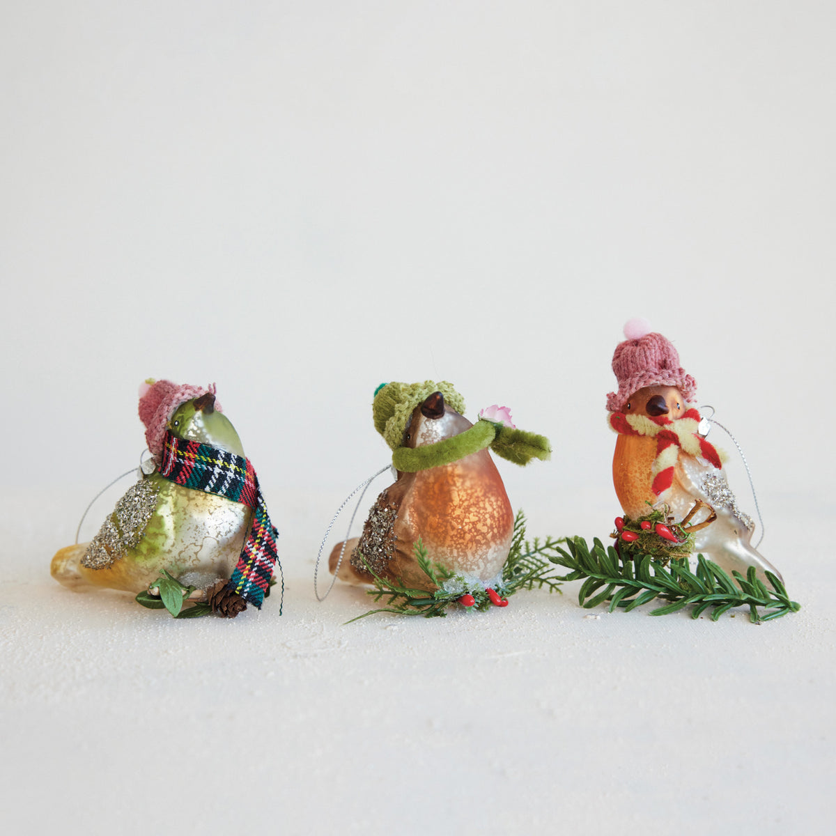 3 bird ornaments wearing hats and scarves sitting next to each other