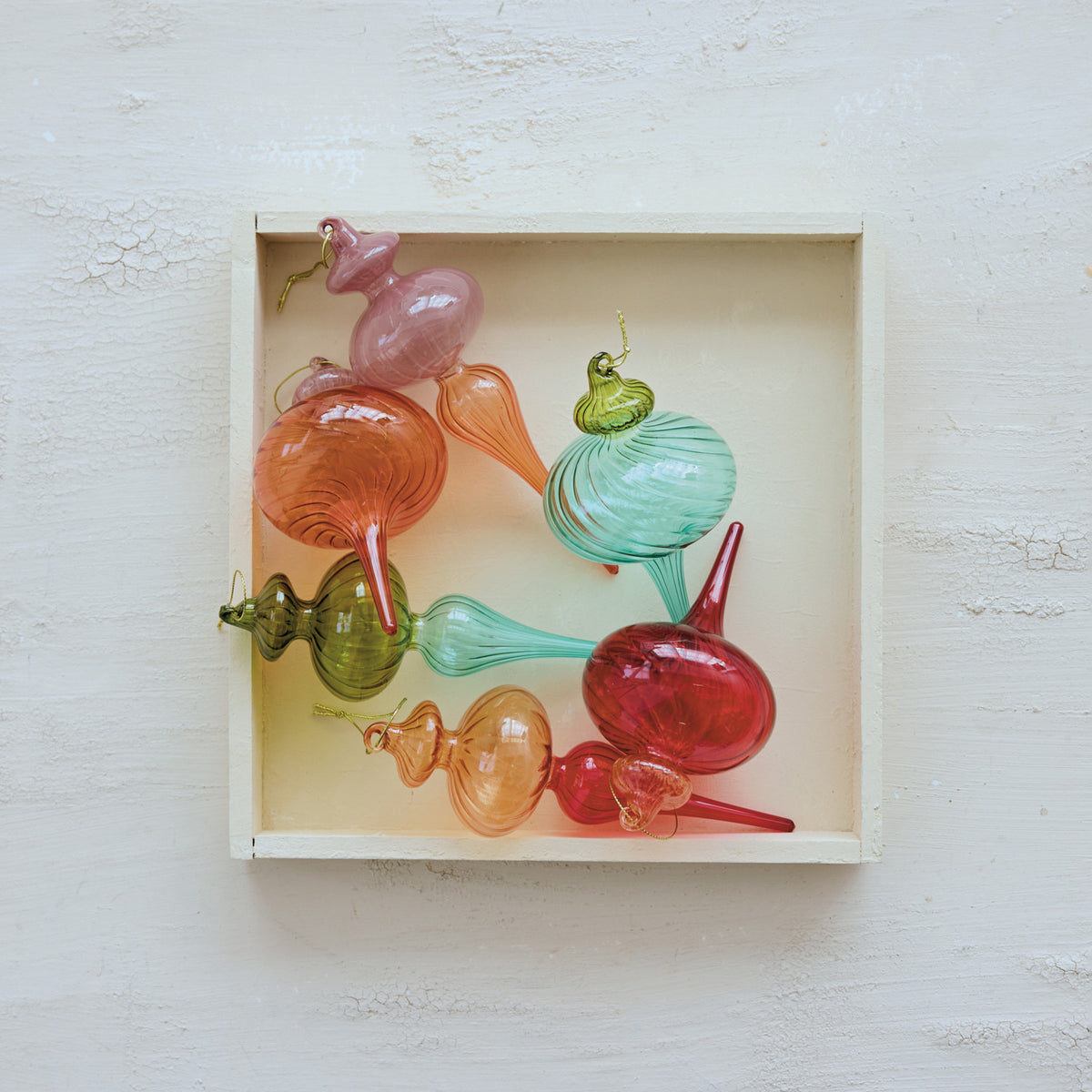 Colorful glass sculptures in a box on a light wooden surface