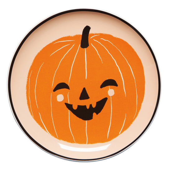 Plate with a smiling pumpkin design on a beige background.