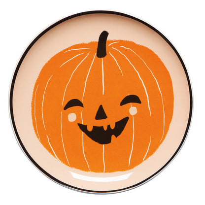 Plate with a smiling pumpkin design on a beige background.