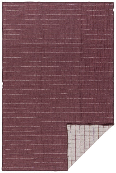 plum dishtowel laying flat with one corner turned up showing reverse side.