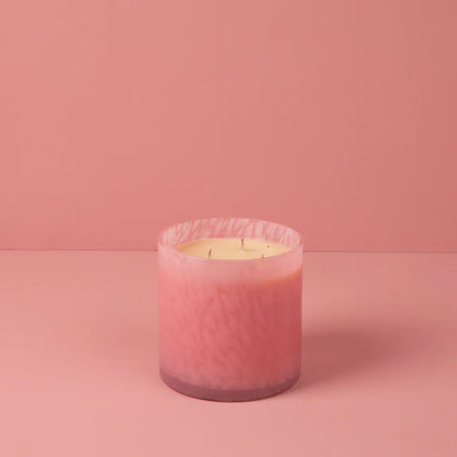 Pink candle in a glass container on a pink background