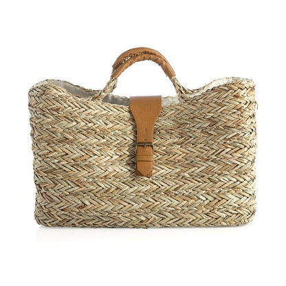 woven seagrass tote bag with buckle flap and handles on white background.