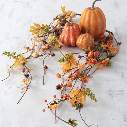 garlands on white table arranged with pumpkins and gourds.