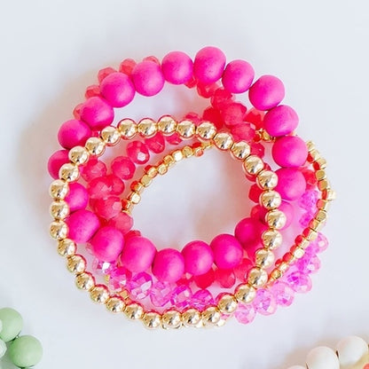 stack of 3 pink and 2 gold stretch bracelets.