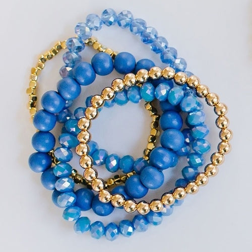 stack of 3 blue and 2 gold stretch bracelets.