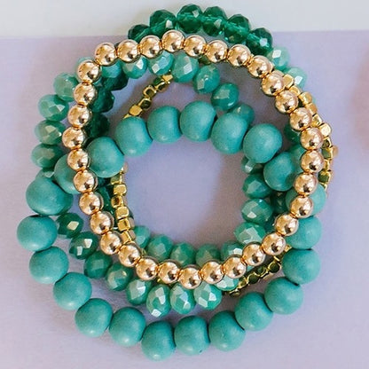 stack of 3 teal and 2 gold stretch bracelets.