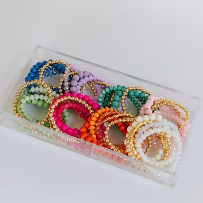 8 stacks of colorful bracelets arranged in an acrylic tray.