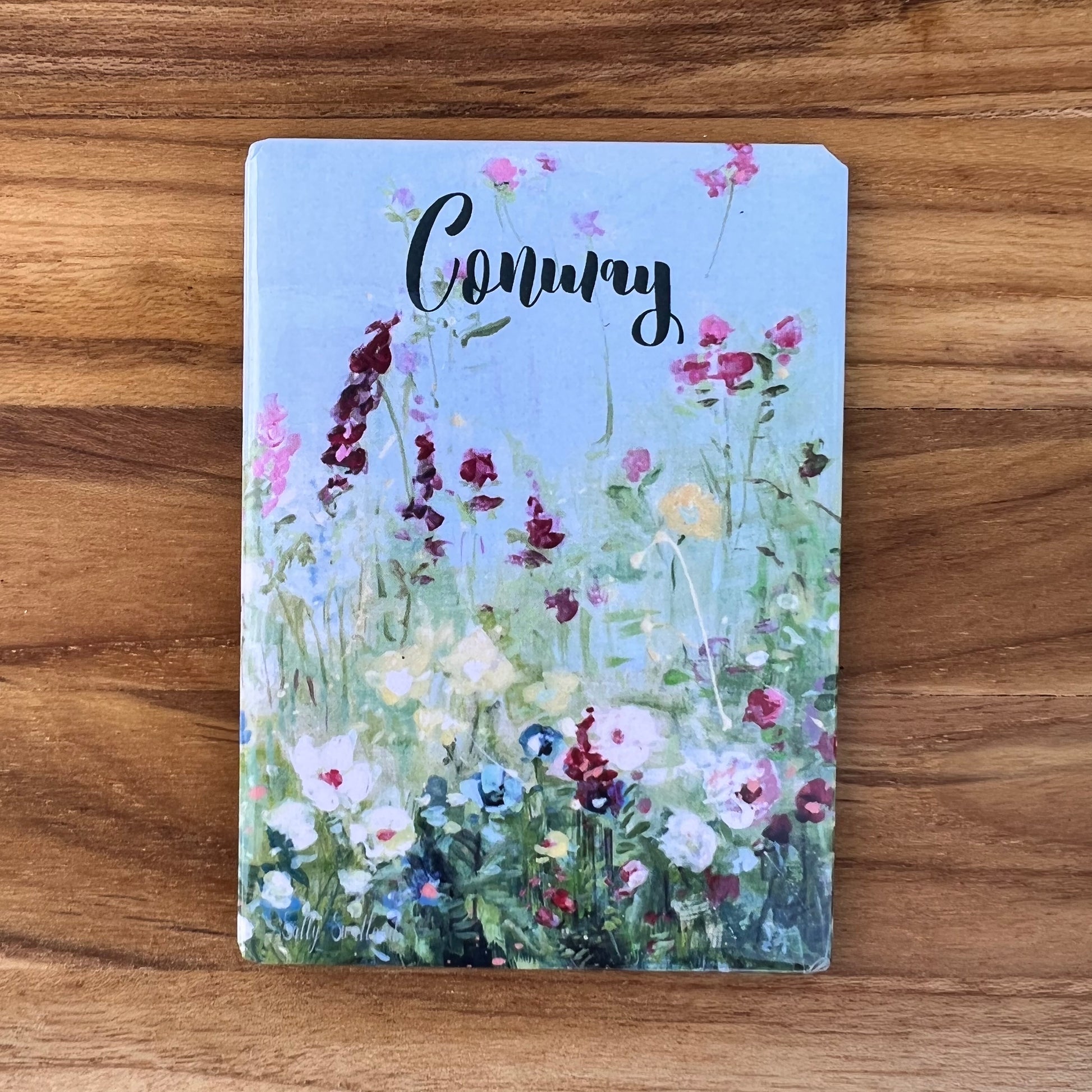 blue magnet with wildflowers and "conway" printed on it.