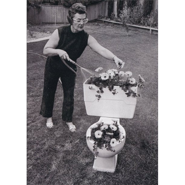front of card is a photograph of a woman watering her flowers planted in a toilet