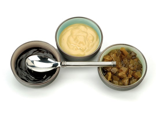 3 bowls of sauces with a stainless steel spoon laying across the.