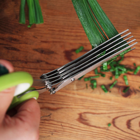 a persons hands illustrating cutting green onions over a wooden surface